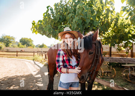 Portrait of cheerful belle jeune femme cowgirl avec son cheval Banque D'Images