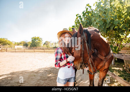 Smiling young woman walking cowgirl avec son cheval dans le village Banque D'Images