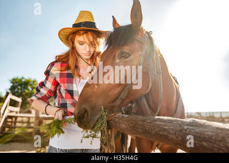 Belle jeune femme rousse en prenant soin de cowgirl et givivn à l'alimentation Banque D'Images