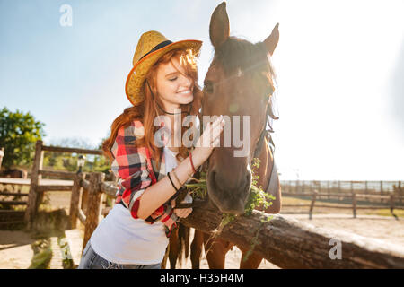 Smiling young woman cowgirl prendre soin et s'étreindre son cheval Banque D'Images