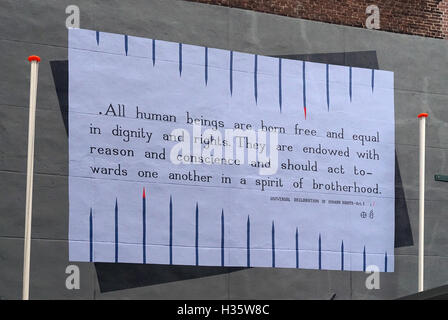 Murale de la Déclaration universelle des droits de l'homme comportant le texte de l'article 1 imprimé sur un panneau blanc stylisé avec des lignes verticales bleues sur un mur extérieur. Banque D'Images