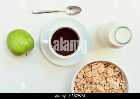 Capture d'un grand angle d'un tableau blanc pour le petit-déjeuner avec une pomme verte, une tasse de café et un bol avec des céréales Banque D'Images