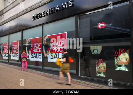 Des problèmes de mise au point floue, les personnes consommateurs chiffres passant la moitié du prix de vente d'automne signes en magasin Debenhams, Manchester, Royaume-Uni. Vente et réductions, promotions & offres spéciales, articles de dégagement, remise, prix, promotion, commerce de détail en magasin Debenhams. Banque D'Images