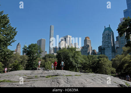 Les enfants jouant sur les juge-arbitre Rock, Central Park. Vue vers le sud en direction de Midtown Manhattan, New York City, New York, United States. Banque D'Images