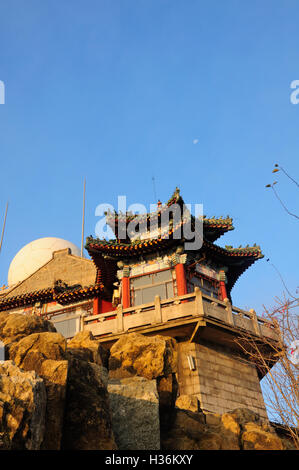 Un bâtiment de style chinois sous une lune décroissante dans la lumière du soleil du matin au sommet du Mont Tai (Taishan) à l'intérieur de la ville de Tai'an Banque D'Images