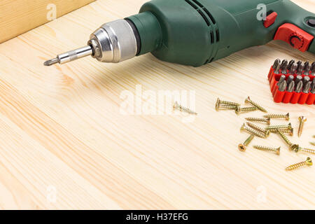 Perceuse électrique avec tournevis et vis sur un fond de bois Banque D'Images