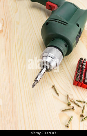 Perceuse électrique avec tournevis et vis sur un fond de bois Banque D'Images