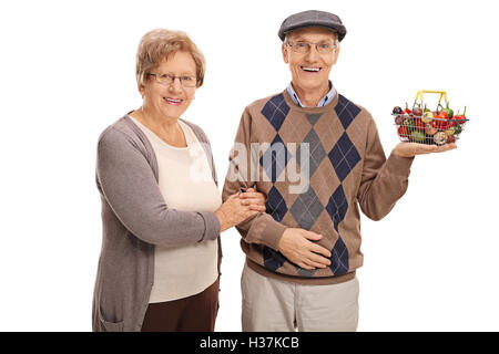 Couple joyeux posant avec un petit panier plein de fruits et légumes frais isolé sur fond blanc Banque D'Images