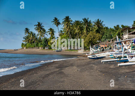 L'Indonésie, Lombok, Selengan, village de pêcheurs, bateaux outrigger sur plage de sable volcanique noir Banque D'Images