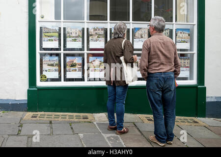 Un homme et une femme sont illustrés à la recherche sur les maisons à vendre à une fenêtre d'agents immobiliers à Bath, Angleterre, Royaume-Uni Banque D'Images