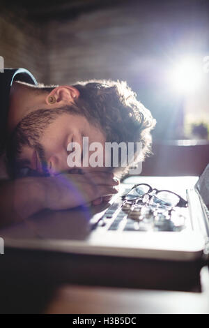 Close-up de l'homme fatigué dormir sur laptop at cafe Banque D'Images