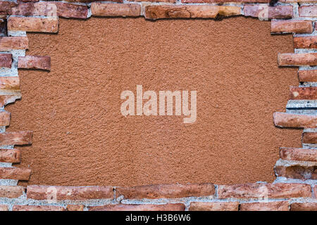 Ancien mur de brique rouge avec un trou sur un bakground orange. Banque D'Images