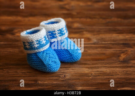 Crochet fait main bleu chaussons pour bébé sur fond de bois, copyspace Banque D'Images