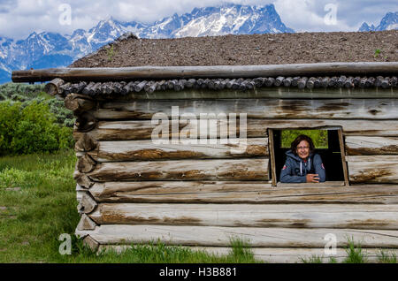 Femme dans la fenêtre de Log Cabin Cunningham historique Parc National de Grand Teton, Wyoming, États-Unis. (MR) Banque D'Images