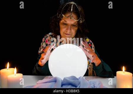 Fortune Teller mature avec boule de cristal, tandis que le plan prévoit Banque D'Images