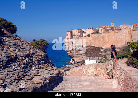 Jeune femme voir Bonifacio situé sur la falaise de calcaire, Bonifacio, côte sud de la Corse, France Banque D'Images