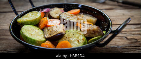 Des légumes grillés sur pot isolé sur table en bois Banque D'Images