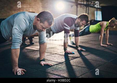 Groupe d'adultes faisant des pompes jusqu'à l'intérieur des Exercices Exercice de remise en forme physique l'entraînement en salle de conditionnement physique avec la lumière vive Banque D'Images