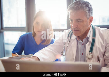 Médecin de discuter avec l'infirmière, au cours d'ordinateur portable Banque D'Images