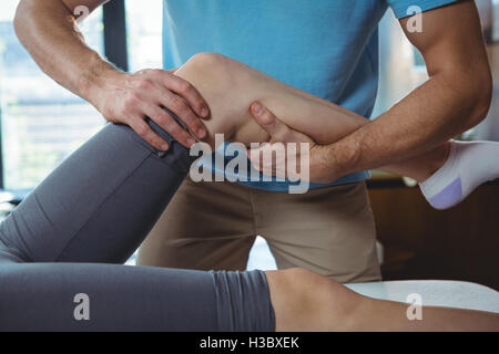 Physiothérapeute mâle à femelle massage du genou donnant patient Banque D'Images