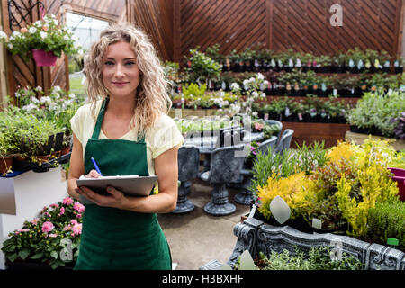 Female florist writing on clipboard Banque D'Images