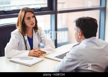 Médecin femme assise à son bureau talking to patient Banque D'Images