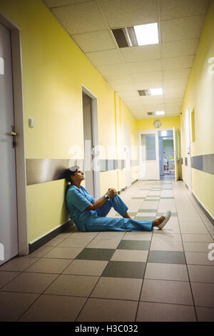 Déprimé Nurse sitting in corridor Banque D'Images