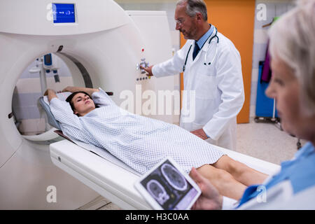 Médecin à la recherche au cerveau irm sur tablette numérique et patient entrant dans la machine irm Banque D'Images