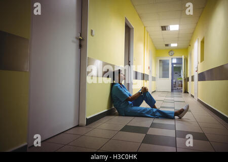 Déprimé Nurse sitting in corridor Banque D'Images