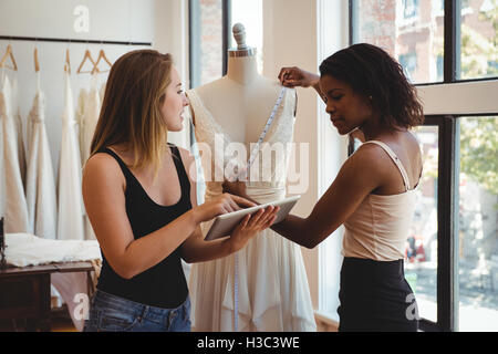 Les créateurs de mode féminine travaillant sur une tablette numérique Banque D'Images