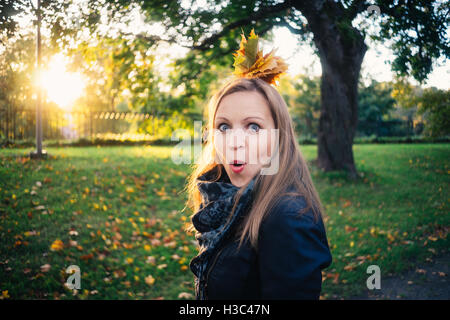 Jeune femme émotionnelle avec tas de feuilles à la surprise dans le parc d'automne. Concept de l'automne Banque D'Images