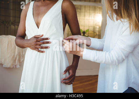 Woman trying on robe de mariage avec l'aide de designer de mode Banque D'Images