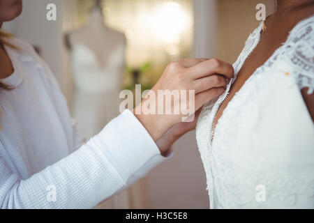 Woman trying on robe de mariage avec l'aide de designer de mode Banque D'Images