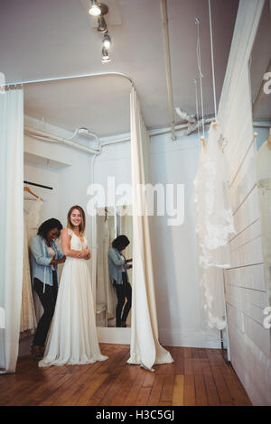 Woman trying on robe de mariage avec l'aide de designer de mode Banque D'Images