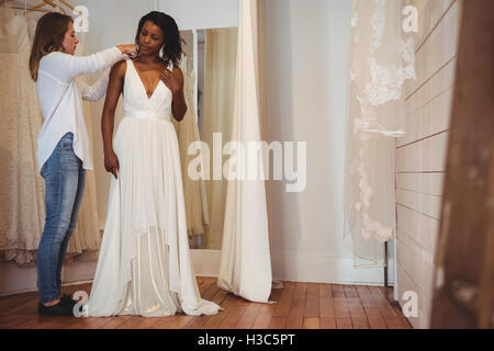 Woman trying on robe de mariage avec l'aide de designer de mode Banque D'Images