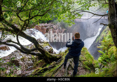 L'homme de prendre une photo sur son téléphone portable de la cascade sur l'eau de Nevis, Glen Nevis Ecosse Royaume-Uni Banque D'Images