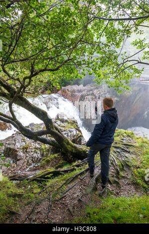 L'homme de prendre une photo sur son téléphone portable de la cascade sur l'eau de Nevis, Glen Nevis Ecosse Royaume-Uni Banque D'Images