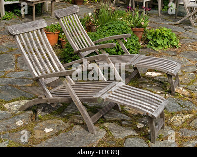 Deux vieux pont en bois chaises longues sur patio en pierre, Colonsay House Gardens, à l'île de Colonsay, Ecosse, Royaume-Uni. Banque D'Images