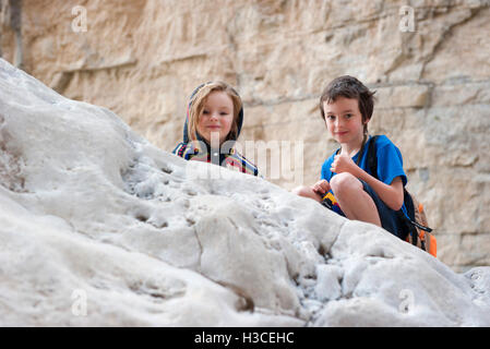 Enfants crouching on rock Banque D'Images