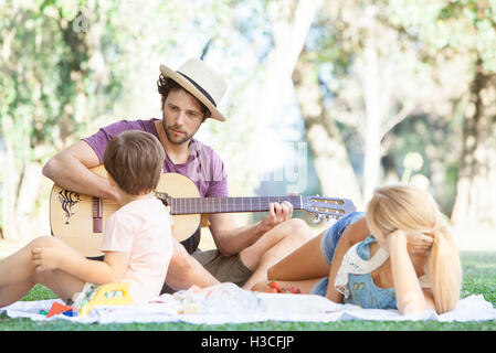 Homme jouant de la guitare acoustique pour l'épouse et fils Banque D'Images