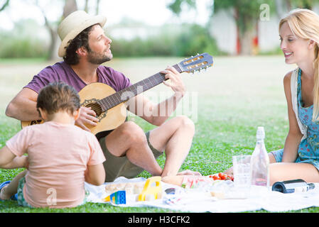Homme jouant de la guitare acoustique en regard de femme et son fils Banque D'Images
