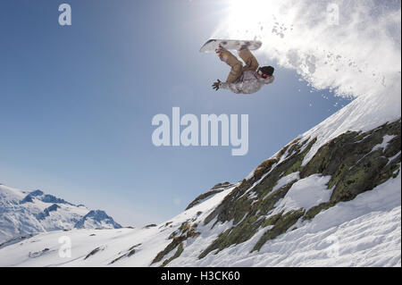 Snowboarder sautant au-dessus d'une falaise dans la station de ski Disentis 3000 Banque D'Images