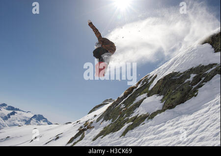 Snowboarder sautant au-dessus d'une falaise dans la station de ski Disentis 3000 Banque D'Images