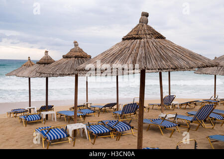 Chaume Tropical parasols sur une plage déserte dans un mauvais temps en Grèce. Banque D'Images