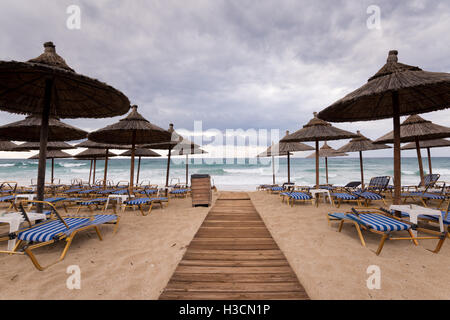 Chaume Tropical parasols sur une plage déserte dans un mauvais temps en Grèce. Banque D'Images