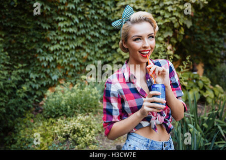 Belle pinup girl joyeuse promenade dans le parc et boisson Banque D'Images