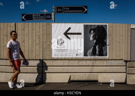 Homme marchant dans les rues de Stockholm et une affiche annonçant une exposition de photos dans le musée avec une photo d'Amy Winehouse. Banque D'Images