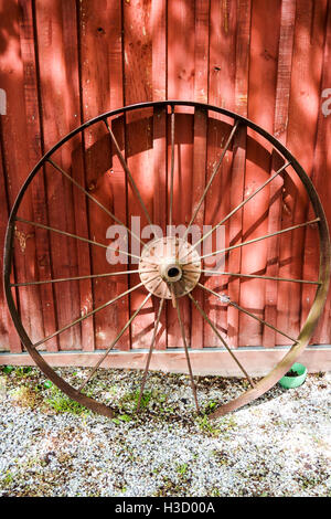 Une roue de métal rouillé châssis reposant contre le mur de la grange. Banque D'Images