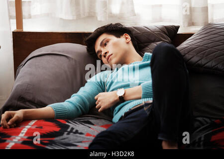 Sad man lying on bed at home Banque D'Images