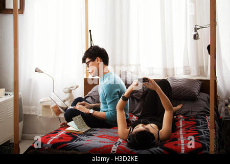 Couple et smart phone tout en vous relaxant dans la chambre Banque D'Images